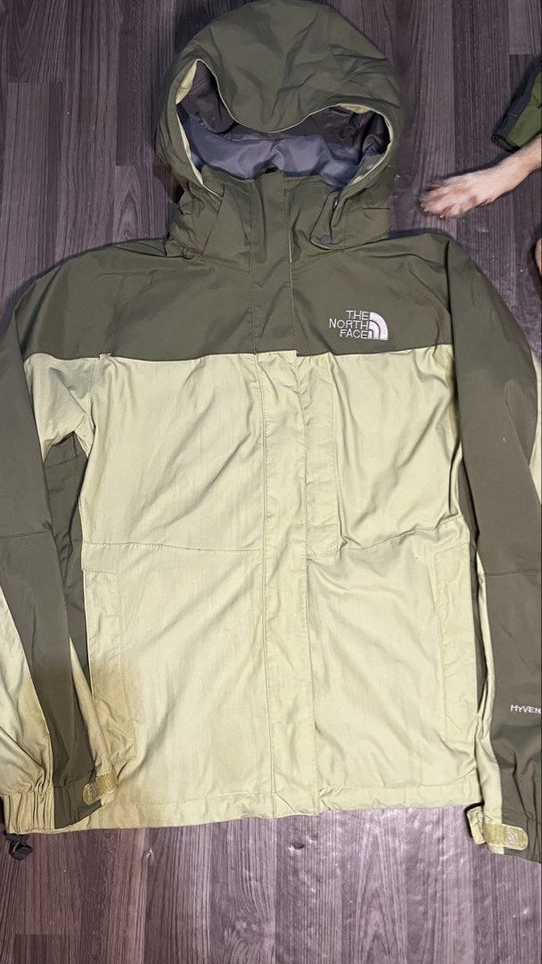 The North Face HyVent Olive Green Jacket (Category: Coats, Jackets and Outerwear) located in Caloocan City. Submitted by lucky_jhonel (Listing ID 1468658705, Image 2). Description: - Brand: The North Face HyVent - Colorway: Olive and light green two-tone - Features: Zip-up front with high collar, adjustable hood, and underarm pit zips for ventilation - Cuffs: Adjustable Velcro straps - Branding: Embroidered logo on chest and sleeve - Condition: E