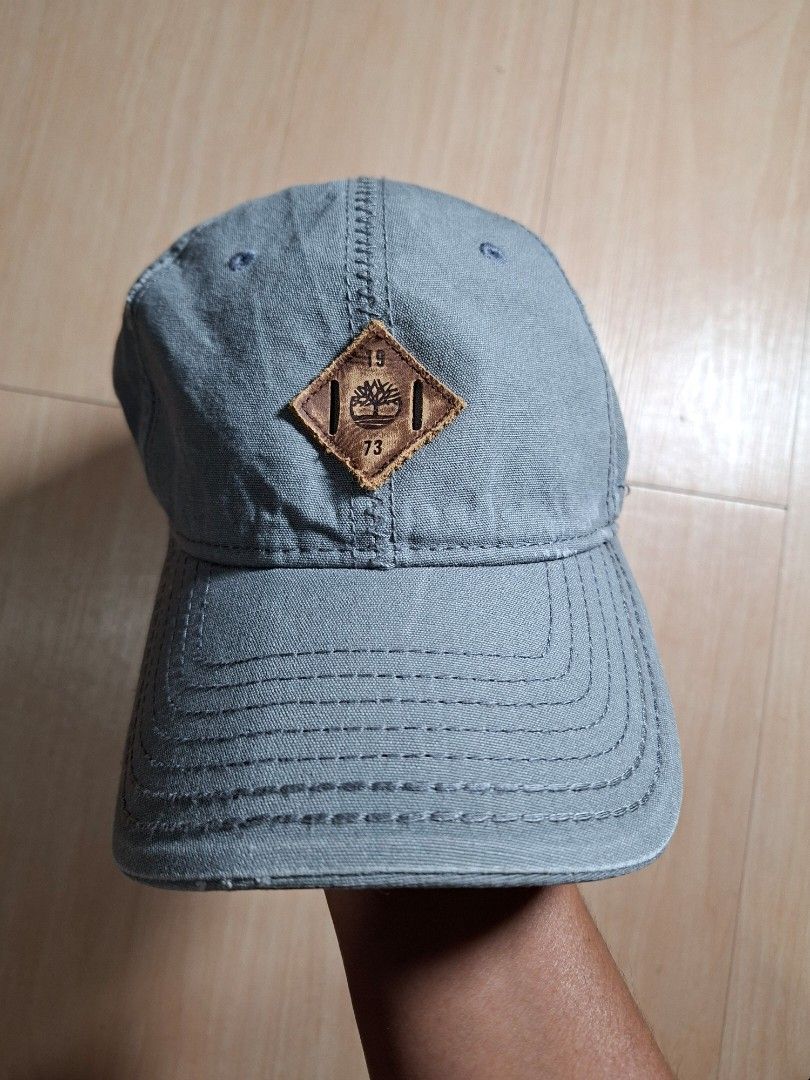 Timberland Grey Baseball Cap with Leather Patch (Category: Caps & Hats) located in Baguio. Submitted by restyrille77846 (Listing ID 1468642511, Image 1). Description: - Authentic Timberland cap in versatile grey - Sturdy canvas material with structured brim and ventilation eyelets - Features iconic diamond-shaped leather patch with tree logo and 1973 branding - Adjustable strap with metal slide buckle and embossed logo clasp - RFS: Closet clearou