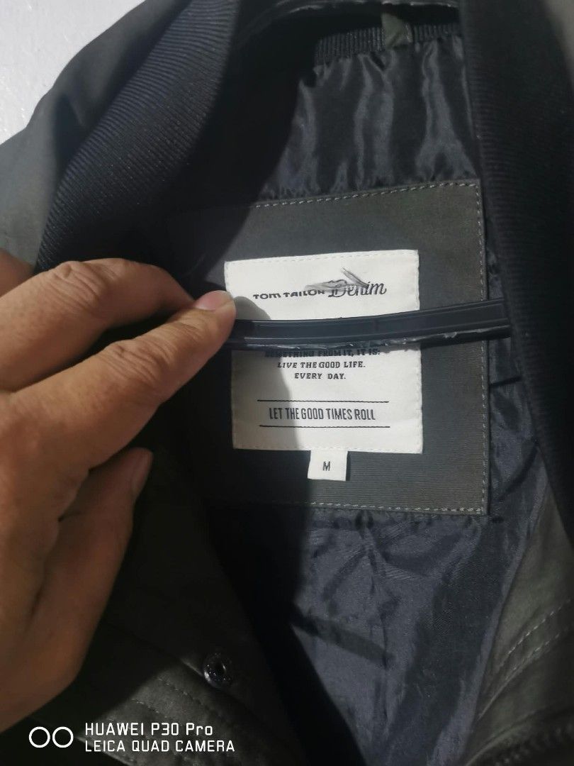 Tom Tailor Denim Green Bomber Jacket Size M (Category: Coats, Jackets and Outerwear) located in Makati City. Submitted by relianzmae57131 (Listing ID 1468644731, Image 1). Description: - Brand: Tom Tailor Denim - Color: Dark Green - Size: Medium (M) - Design: Button-up front, flap pockets, and large "ADVANCED NEW URBAN WAYS HAMBURG DENIM BRAND" back graphic - Interior: Soft grey fabric lining for extra comfort - Condition: Great weight, ideal for