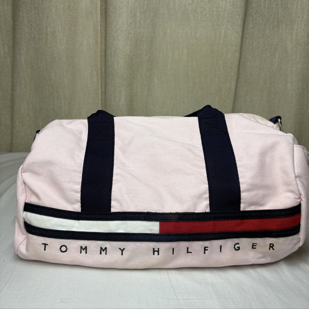 Tommy Hilfiger Pink Canvas Small Duffel Bag (Category: Shoulder Bags) located in Angeles City. Submitted by muse_archive (Listing ID 1468632539, Image 1). Description: -Tommy Hilfiger with dark blue shoulder strap and carry handles - Top zip closure with dark interior lining -issues: some yellowish staining (hindi masyadong halata) -super clean ng interior .