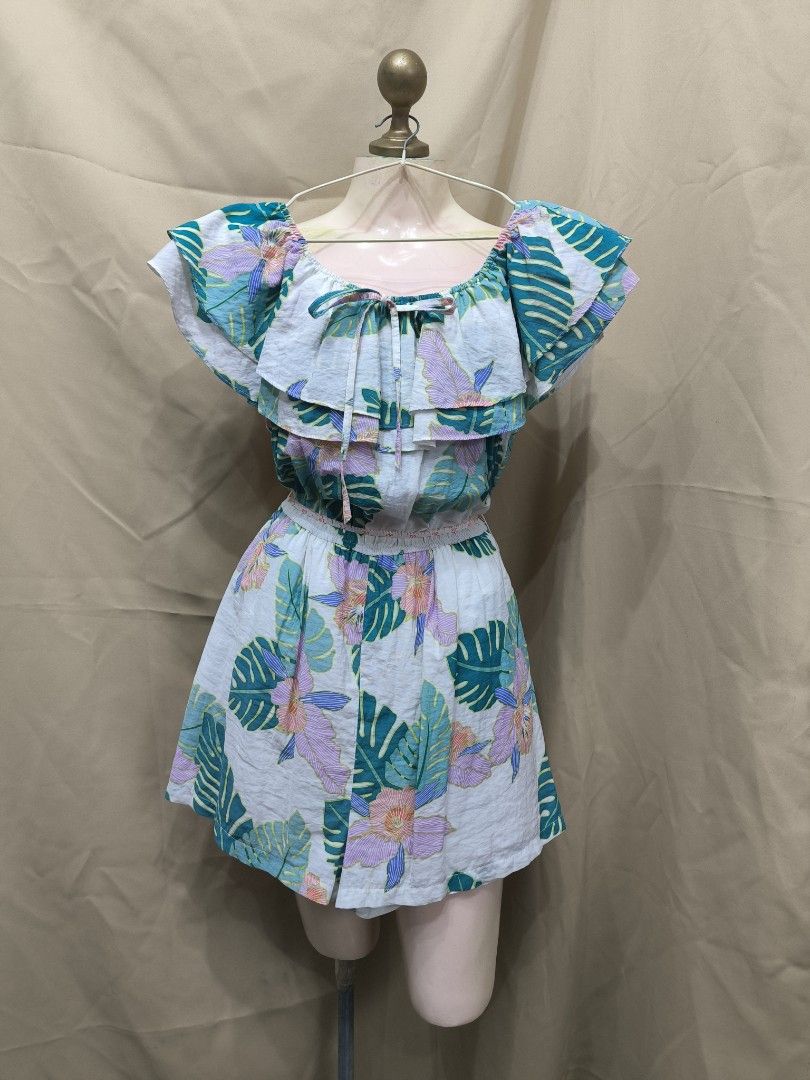 Tropical Floral Print Off-Shoulder Ruffle Romper (Category: Rompers) located in Marikina City. Submitted by mrlfashion23 (Listing ID 1468596181, Image 1). Description: - Tropical print: White with pink flowers and green monstera leaves - Design: Ruffle overlay, sweet neckline tie, and flutter sleeves - Comfort: Elastic waistband for an easy, comfortable fit - Occasion: Ideal for sunny days, beach trips, and vacays.