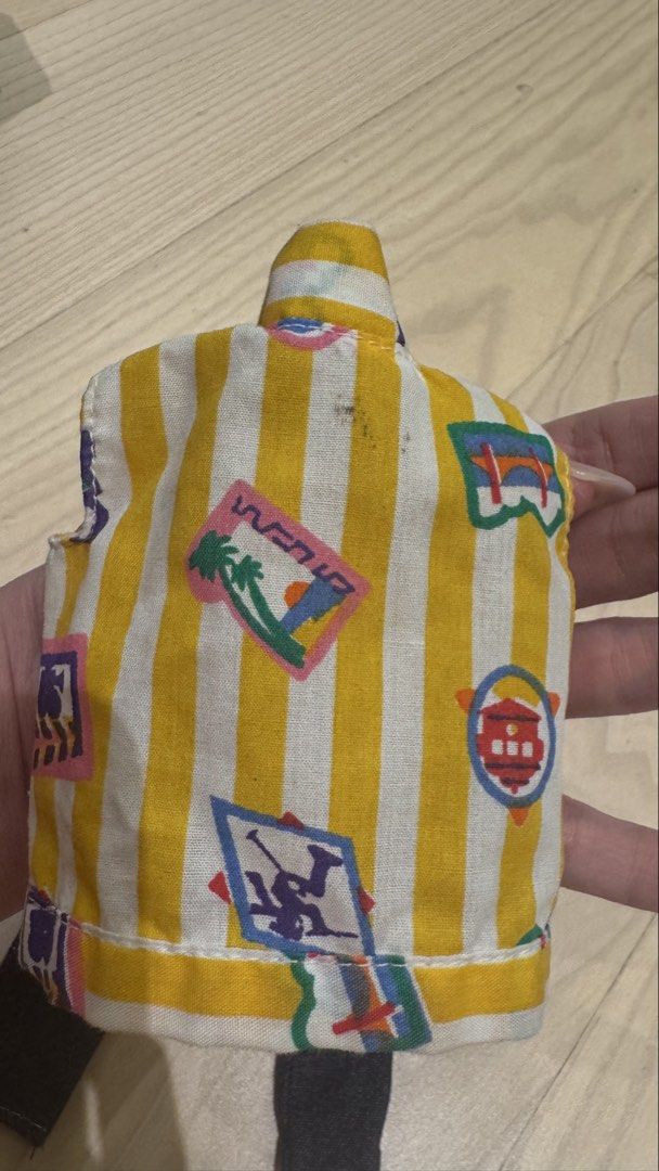 Vintage ken Doll vest (Category: Sleeveless) located in Mandaluyong City. Submitted by maelovestoshop (Listing ID 1468689689, Image 3). Description: - Item: Doll outfit (Vest and Denim Pants) - Top: Yellow and white striped vest with colorful tropical graphics and travel stamp motifs - Bottoms: Matching dark blue denim pants - Fit: Standard fashion dolls - Condition: Good, with minor age spots and discoloration on the vest collar/shoulder (see cl