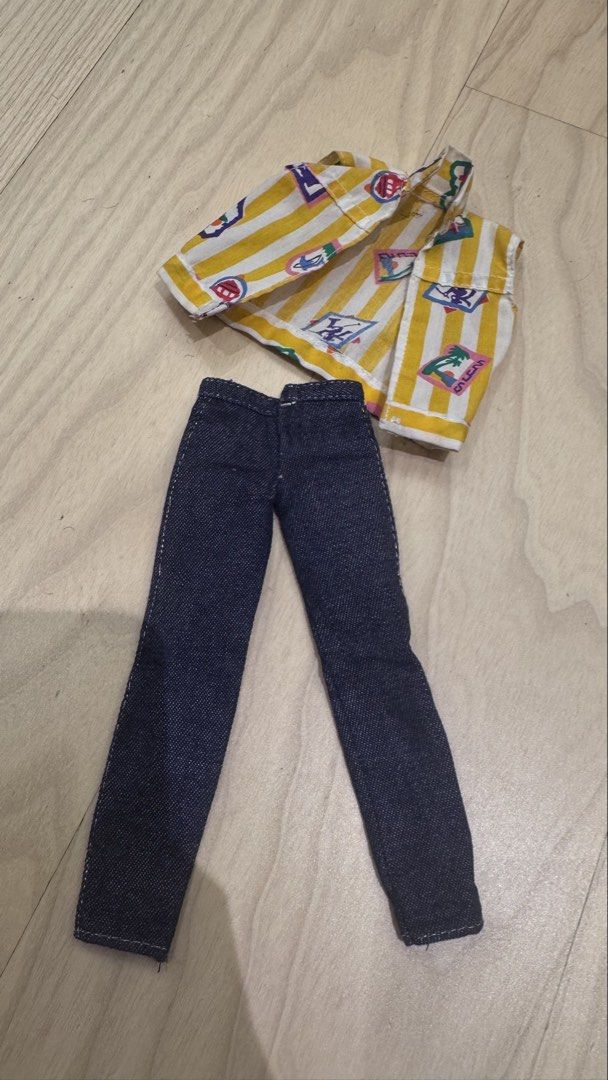 Vintage ken Doll vest (Category: Sleeveless) located in Mandaluyong City. Submitted by maelovestoshop (Listing ID 1468689689, Image 1). Description: - Item: Doll outfit (Vest and Denim Pants) - Top: Yellow and white striped vest with colorful tropical graphics and travel stamp motifs - Bottoms: Matching dark blue denim pants - Fit: Standard fashion dolls - Condition: Good, with minor age spots and discoloration on the vest collar/shoulder (see cl