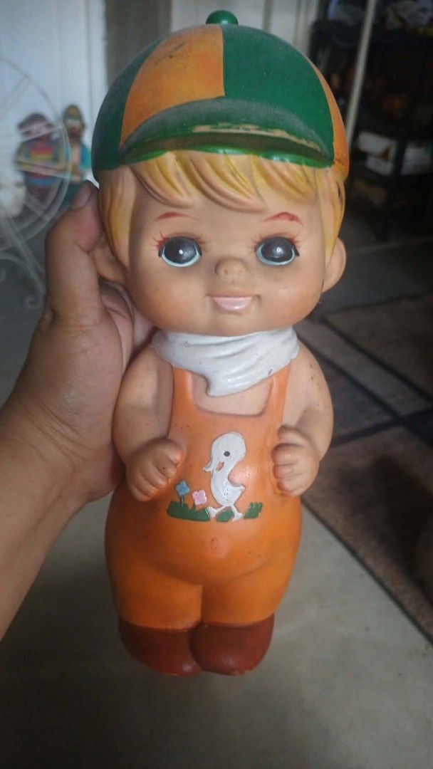 Vintage Rubber Doll with Cap and Overalls (Category: Kids Toys) located in Mandaluyong City. Submitted by LEATHERFACE (Listing ID 1468552259, Image 1). Description: - Vintage rubber squeaker doll in a standing pose - Outfit includes orange overalls with a cute white duck graphic - Wears a green and orange cap, white neck scarf, and brown shoes - Styled with blonde hair - Condition: Normal aging throughout with minor paint wear on the cap brim - P