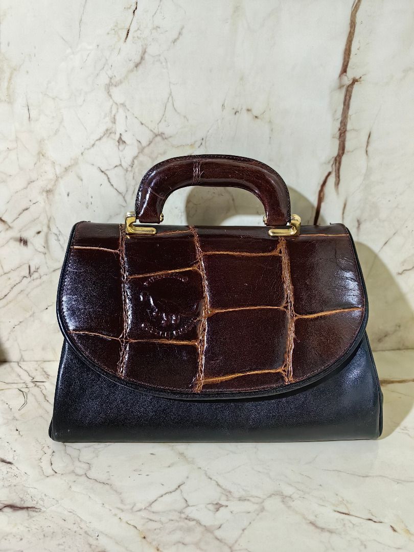 Vintage Two-Tone Crocodile Pattern Structured Handbag ion (Category: Luxury Bags & Wallets) located in Tarlac. Submitted by jeremiah.curator.2026 (Listing ID 1468663849, Image 1). Description: - Vintage structured handbag in a chic brown and black colorway - Glossy crocodile-embossed flap top paired with a smooth black leather base - Elegant top handle accented with gold-tone hardware - Convenient exterior zippered pocket on the back - Protective