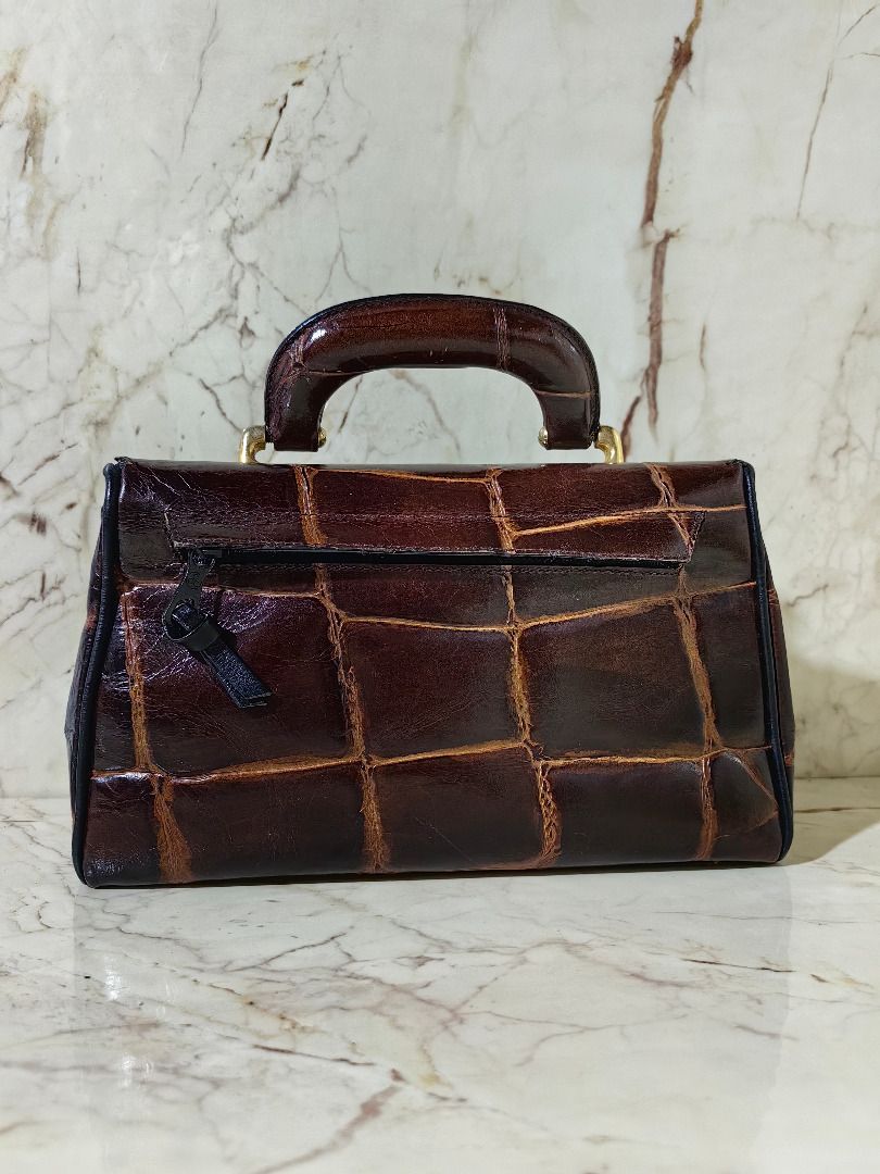 Vintage Two-Tone Crocodile Pattern Structured Handbag ion (Category: Luxury Bags & Wallets) located in Tarlac. Submitted by jeremiah.curator.2026 (Listing ID 1468663849, Image 3). Description: - Vintage structured handbag in a chic brown and black colorway - Glossy crocodile-embossed flap top paired with a smooth black leather base - Elegant top handle accented with gold-tone hardware - Convenient exterior zippered pocket on the back - Protective