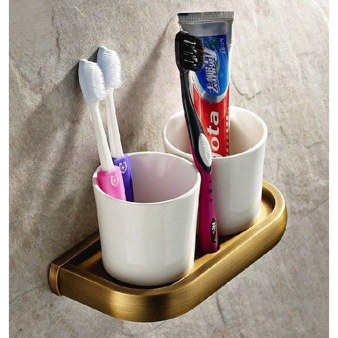 Wall-mounted brass toothbrush holder with two white cups (Category: Bathroom & Kitchen Fixtures) located in Makati City. Submitted by secondhand_finds (Listing ID 1468599829, Image 1). Description: - Wall-mounted toothbrush and toothpaste organizer - Antique bronze finish metal tray with two white ceramic cups - Frees up bathroom counter space completely - Easy to install near your sink or mirror - Sturdy base fits standard toothpaste tubes and b