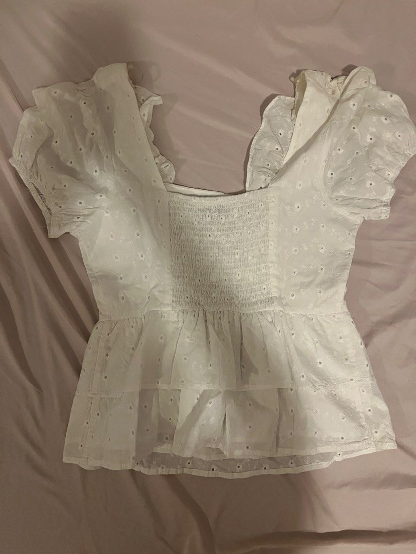 White eyelet ruffle crop top with puff sleeves (Category: Blouses) located in Manila. Submitted by vees.shop (Listing ID 1468683809, Image 2). Description: - Color: White with all-over floral eyelet embroidery - Material: Lightweight, breathable cotton - Neckline: Square neck with cute ruffle trim - Sleeves: Trendy puffed short sleeves - Fit: Stretchy smocked back panel for a snug fit - Style: Tiered peplum hem for a flattering shape - Ideal for: