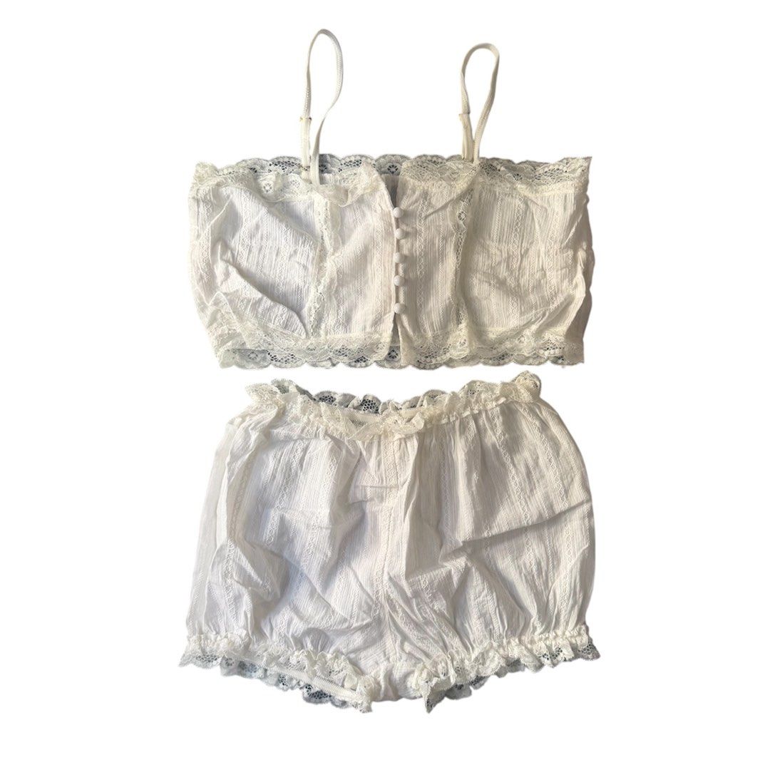 White Lace Pajama Set (Category: Undergarments & Loungewear) located in Marikina City. Submitted by lou.and.trio (Listing ID 1468568541, Image 2). Description: - Condition: Used once - Color: White with subtle vertical textured stripes - Set includes: Cami top and matching shorts - Top features: Adjustable straps and cute pearl-like front buttons - Shorts features: Elastic waistband and ruffled lace hems - Fit: For small frames 26” - 28” - Bought