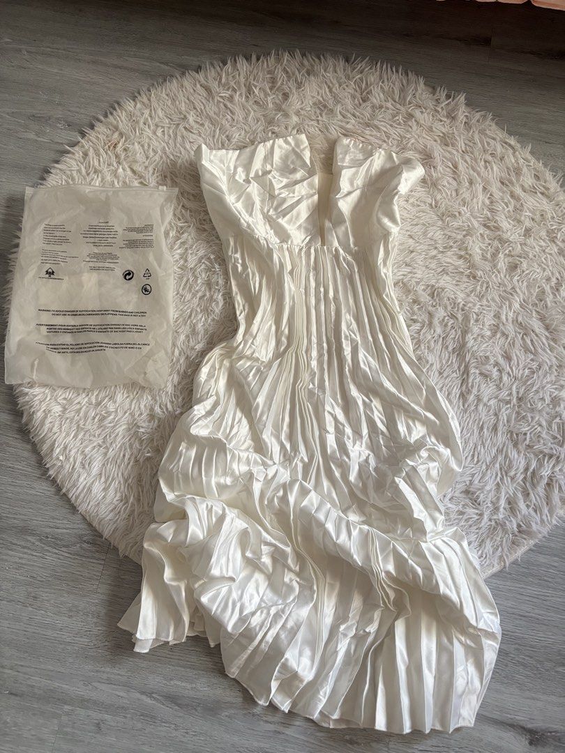White Pleated Strapless Midi Dress (Category: Dresses) located in Quezon City. Submitted by lovedbysloane (Listing ID 1468596439, Image 1). Description: - Style: Strapless midi dress with a deep front split neckline - Material: Glossy satin with all-over pleats - Condition: Brand new, never worn, tags still attached - Packaging: Comes in original plastic storage bag - Color: White.