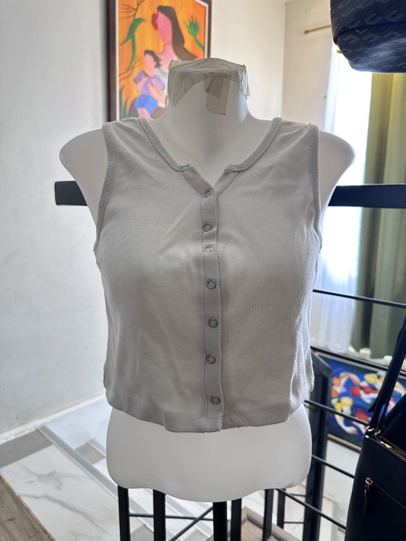 White ribbed button-down crop tank top (Category: Sleeveless) located in Manila. Submitted by rachael_23 (Listing ID 1468527369, Image 1). Description: - Color: White - Style: Ribbed crop top with button-front closure and scoop neckline - Fit: Sleeveless, cropped length, good stretch - Material: Soft cotton-blend rib knit - Condition: Clean and well-maintained - Perfect for: Casual everyday wear, easily paired with high-waisted jeans or skirts.
