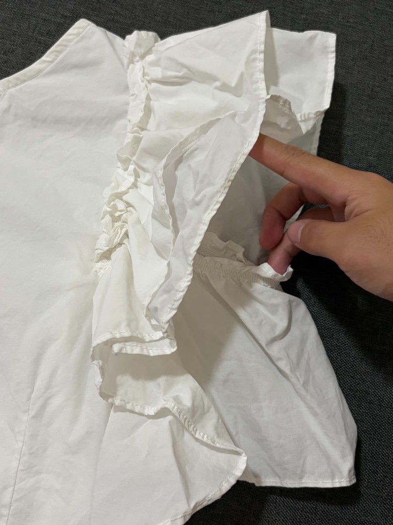 White Ruffle Sleeve Blouse with Button-Up Back (Category: Blouses) located in Lipa City. Submitted by xandibaronix (Listing ID 1468687480, Image 3). Description: - Color/Material: White cotton, lightweight and breezy - Design: Dramatic layered ruffle sleeves with button-up closure at the back - Condition: Pre-loved with small stains (fixable with a quick wash or spot clean) - Style Tip: Pair with jeans or a skirt for a chic, effortless look! - Ca