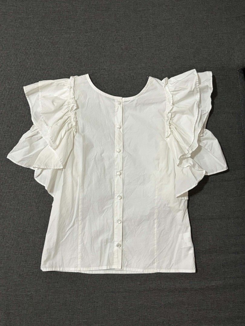 White Ruffle Sleeve Blouse with Button-Up Back (Category: Blouses) located in Lipa City. Submitted by xandibaronix (Listing ID 1468687480, Image 1). Description: - Color/Material: White cotton, lightweight and breezy - Design: Dramatic layered ruffle sleeves with button-up closure at the back - Condition: Pre-loved with small stains (fixable with a quick wash or spot clean) - Style Tip: Pair with jeans or a skirt for a chic, effortless look! - Ca