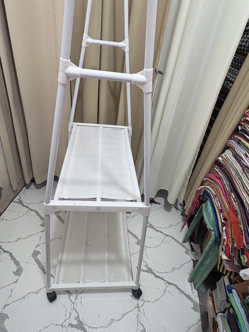 White Triangle Clothes Rack With Shelves And Wheels (Category: Shelves, Cabinets & Racks) located in Quezon City. Submitted by geminiselection (Listing ID 1468565362, Image 3). Description: Issue: nagkaroon ng small hole sa baba, please check last pic. Maliit lang po, doesn’t affect the functionality of the item. - with wheels, still working.