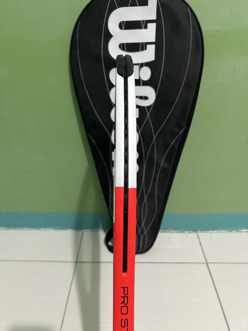 Wilson Pro Staff Comp Tennis Racket with Cover (Category: Racket and Ball Sports) located in Imus. Submitted by storiesforstrays (Listing ID 1468638718, Image 2). Description: Wilson Pro Staff Comp tennis racket. Orange, white, and black colorway. Strung and ready to play. Includes the original Wilson black racket cover bag with zip closure. Frame is clean with minimal scuffs. .