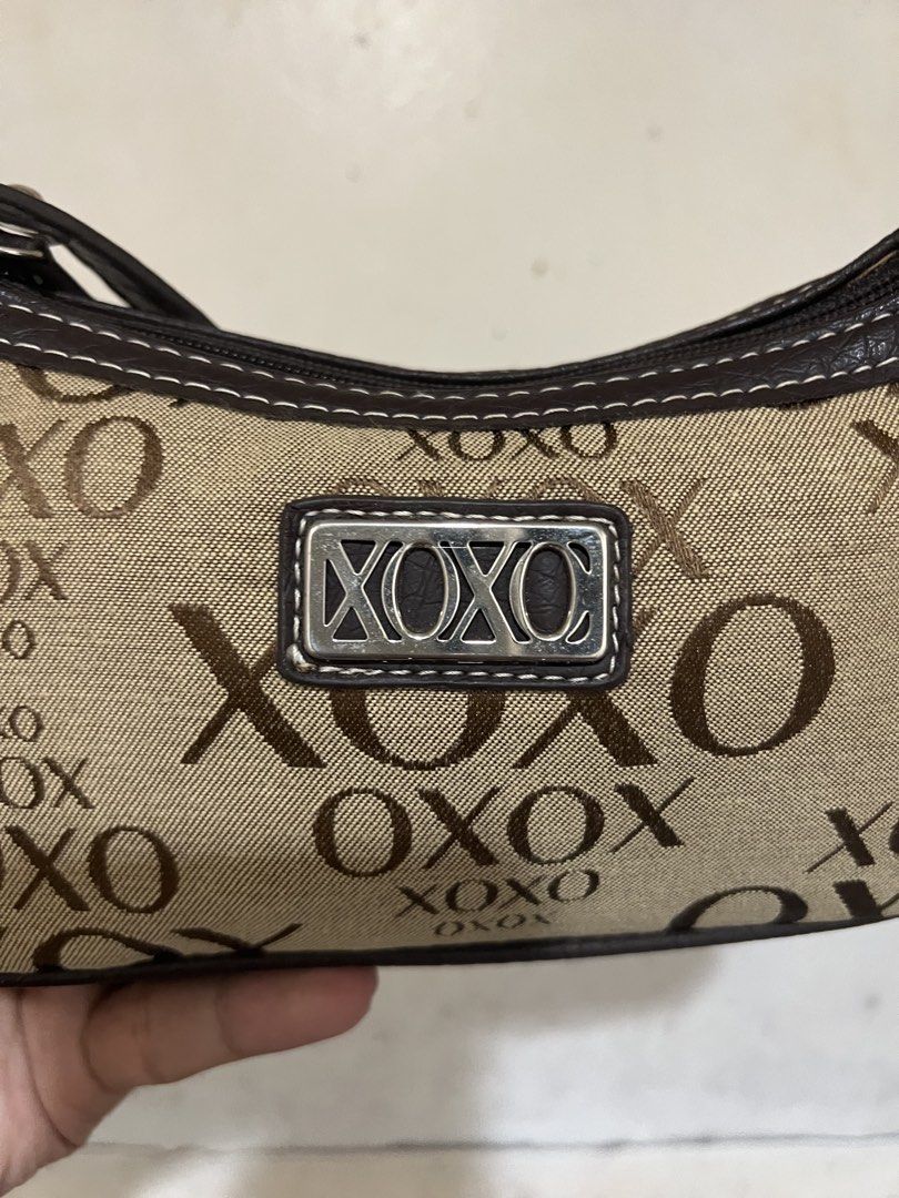 XOXO Accessories Monogram Shoulder Bag (Category: Shoulder Bags) located in Alburquerque. Submitted by ukaydecebuofficial (Listing ID 1468564518, Image 3). Description: - Brand: XOXO - Design: Brown and beige monogram print with faux leather trim and white contrast stitching - Hardware: Silver-tone with front metal logo plate - Closure: Secure zip top - Interior: Clean with fabric care tags intact - Size: Compact, perfect for everyday essentials.