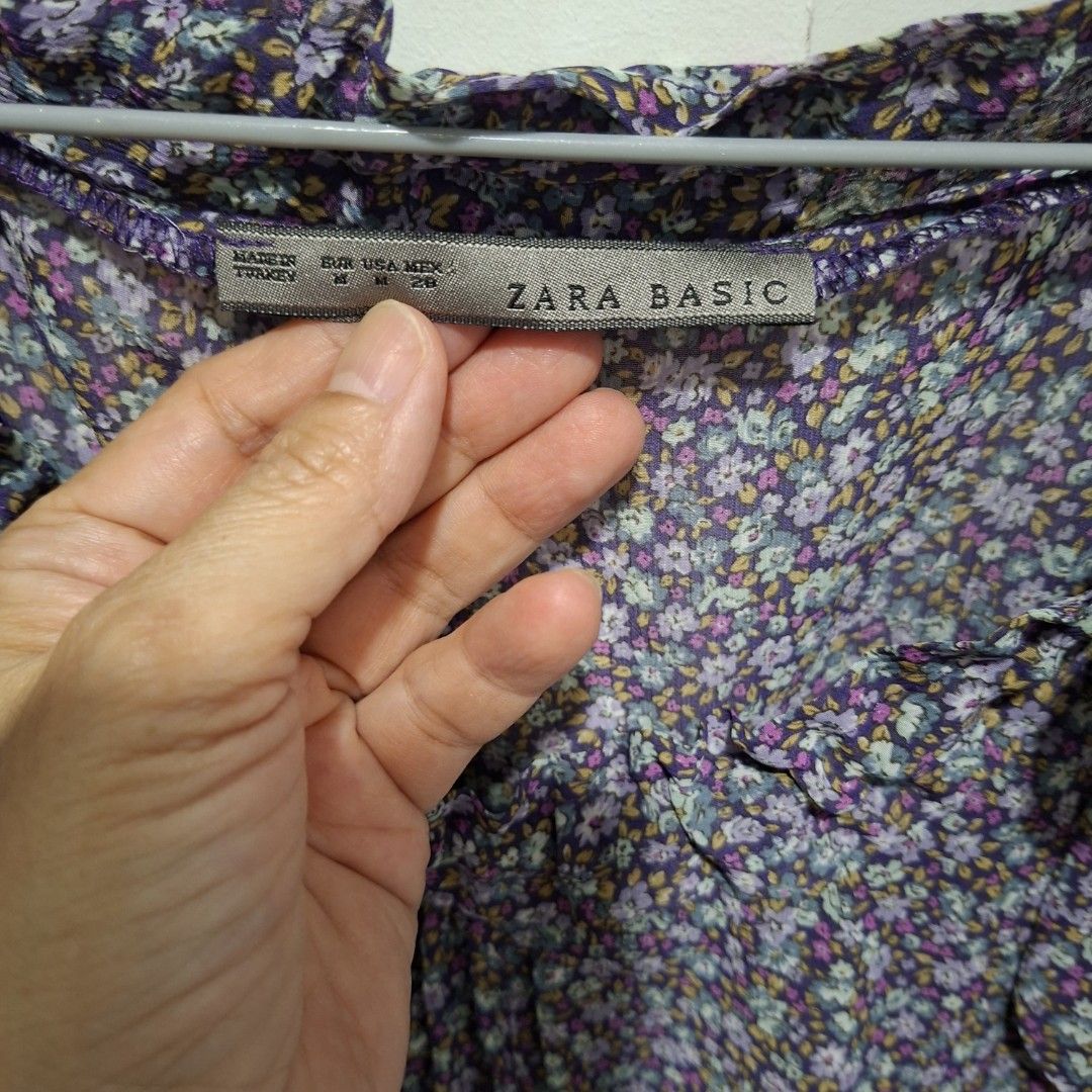 Zara Basic Floral Print Short Sleeve Blouse (Category: Blouses) located in Imus. Submitted by jgz21 (Listing ID 1468673710, Image 2). Description: - Brand: Zara Basic - Size: M - Design: Purple floral print with ruffled neckline and shoulders - Sleeves: Short sleeves - Material: Lightweight and comfortable - Style: Easy to dress up or down for casual days.