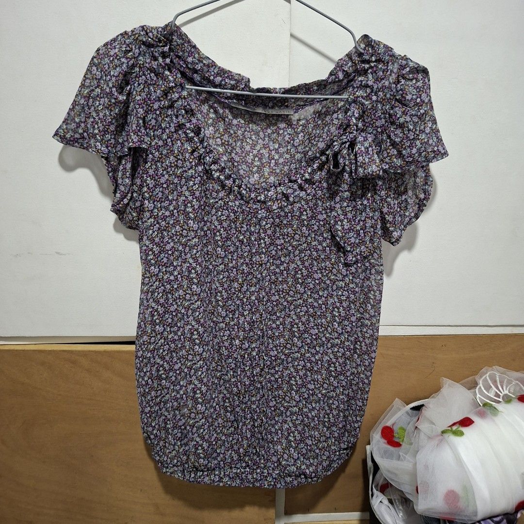 Zara Basic Floral Print Short Sleeve Blouse (Category: Blouses) located in Imus. Submitted by jgz21 (Listing ID 1468673710, Image 1). Description: - Brand: Zara Basic - Size: M - Design: Purple floral print with ruffled neckline and shoulders - Sleeves: Short sleeves - Material: Lightweight and comfortable - Style: Easy to dress up or down for casual days.