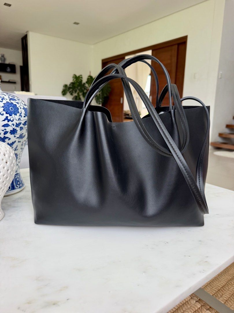 Zara Black Tote Bag (Category: Tote Bags) located in Lipa City. Submitted by pauline0303 (Listing ID 1468710963, Image 2). Description: - Authentic ZARA black tote bag - Double shoulder straps for comfortable carry on the shoulder or arm - Structured base keeps the bag upright - Center zippered compartment divides the interior - Clean black lining with embossed ZARA brand patch - Minimalist design perfect for daily commutes or errands - Flaw on s