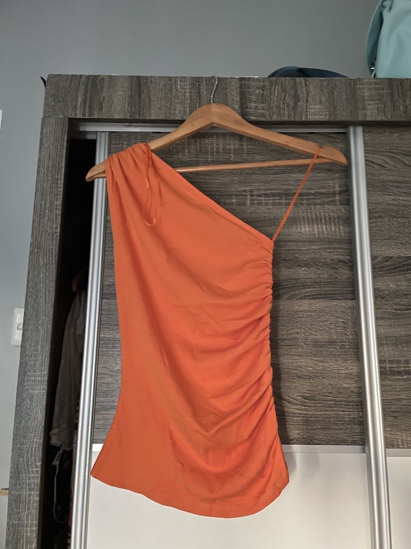 Zara Orange Asymmetric Ruched Top (Category: Sleeveless) located in Manila. Submitted by iyaalexi (Listing ID 1468665847, Image 2). Description: - Brand: Zara - Style: One-shoulder with thin strap on the other side - Color: Vibrant orange - Fit: Fully ruched down the side for a fitted, flattering look - Fabric: Stretchy and super comfortable - Condition: Great, with a clean tag inside - Perfect for: Summer days or nights out.