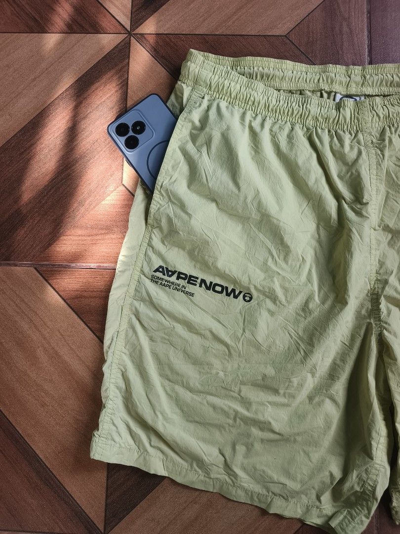 Aape By A Bathing Ape Nylon Short (Category: Shorts) located in Zamboanga. Submitted by d2977250664046 (Listing ID 1468879407, Image 2). Description: - Brand: Aape - Item: Nylon Shorts - Color: Light Green - Size: Large (34-36x20) - Waistband: Elastic with branded white drawstrings - Details: 'APE NOW' text print on right leg, circular Aape logo patch on left thigh, and small woven hem tag - Back: 'Somewhere in the Aape Universe' branding tag - P