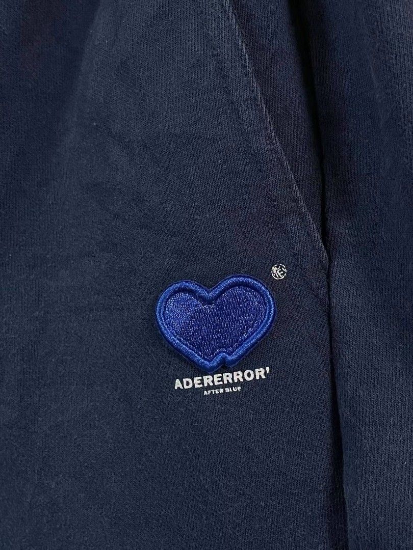 Ader Error Heart Sweatshorts Navy Blue (Category: Shorts) located in Manila. Submitted by ayskrim_ (Listing ID 1468788892, Image 3). Description: - Brand: Ader Error - Color: Navy Blue - Dimes: Length: 18 Leghole: 12 Waistline: 28-34 - Material: Premium thick cotton - Waistband: Elastic with adjustable drawstrings and branded metal aglets - Details: Blue embroidered heart patch with 'ADERERROR' and 'AFTER BLUE' lettering, side hem logo tag.