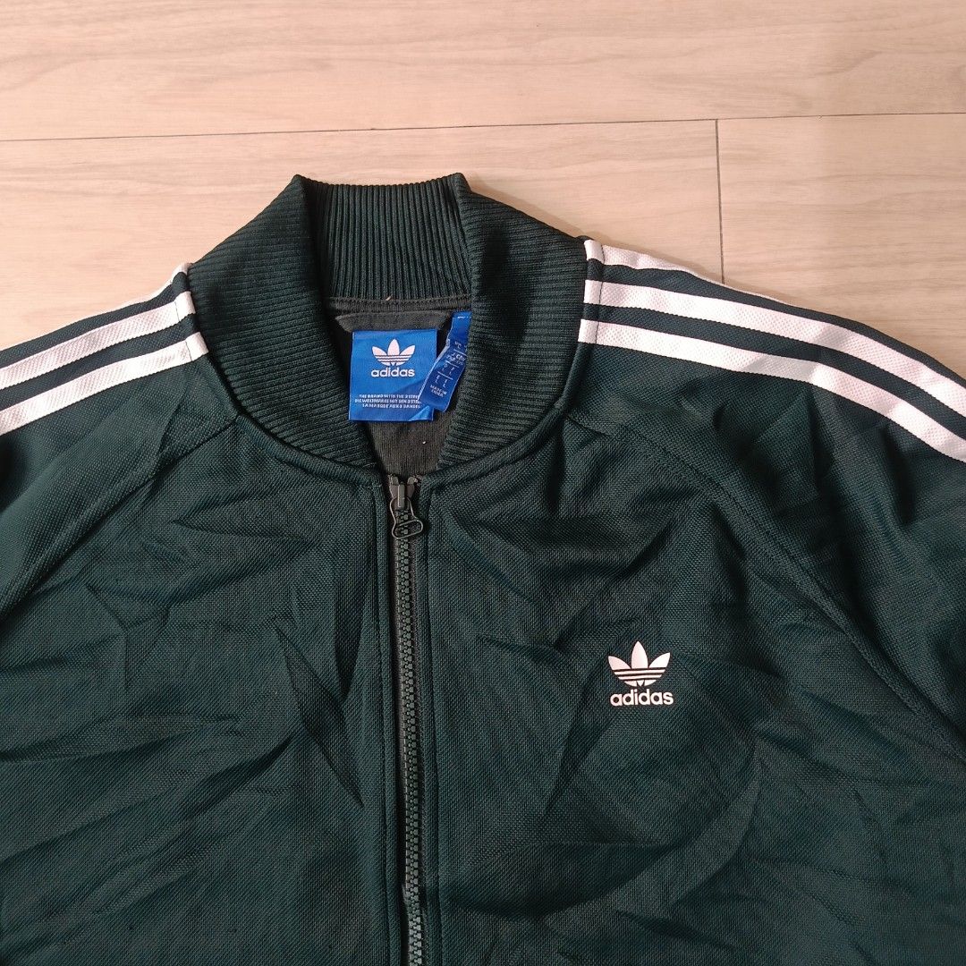 Adidas Dark Green Track Jacket Full Zip (Category: Coats, Jackets and Outerwear) located in Manila. Submitted by ghello99 (Listing ID 1468848118, Image 2). Description: - Authentic dark green Adidas track jacket - Classic white three stripes on sleeves with embroidered trefoil logo on chest - Full front zip with comfortable ribbed collar, cuffs, and hem - Convenient front zip pockets - Material: 67% polyester, 33% cotton blend (standard fit) - Co