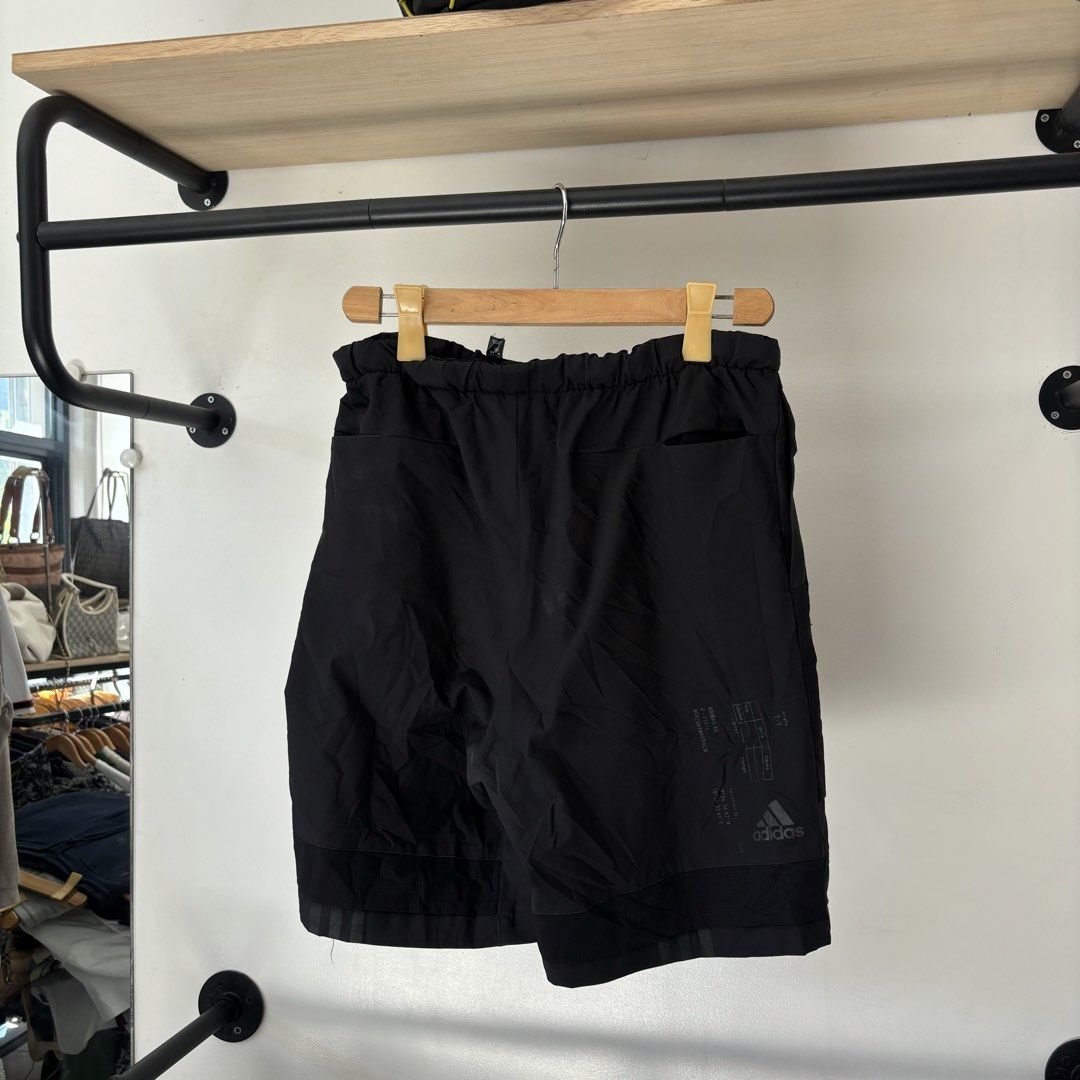 Adidas M Tech Shorts Black Size L (Category: Shorts) located in Bambang. Submitted by heats777 (Listing ID 1468818036, Image 2). Description: - Brand: Adidas - Style: M Tech Shorts / Techwear - Size: L - Material: 100% polyester - Waist: Elastic with bright pink integrated belt buckle closure - Details: Techwear graphics printed near the bottom hem on the back, multiple utility pockets - Condition: Clean, excellent overall condition.