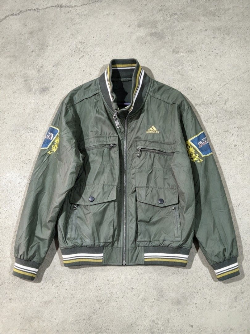 Adidas Olive Green Bomber Jacket with Patches (Category: Coats, Jackets and Outerwear) located in Manila. Submitted by nisayy13 (Listing ID 1468783759, Image 1). Description: - Color: Olive green with gold embroidery logo - Pockets: Dual chest zip pockets and lower snap-button pockets - Details: Blue and yellow patches on both sleeves, full front zip closure - Trim: Striped ribbed collar, cuffs, and hem - Fit/Material: Heavy-duty material with a 