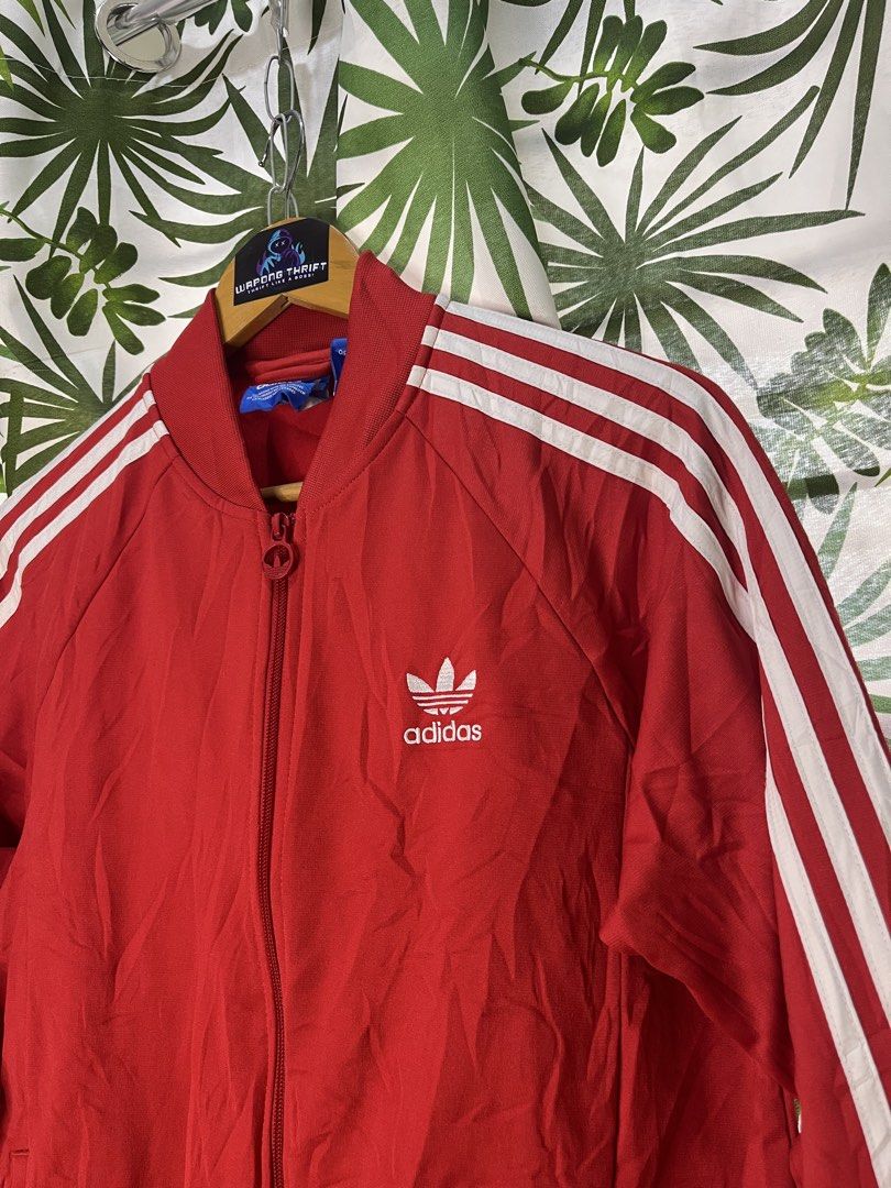 Adidas Trackjacket (Category: Coats, Jackets and Outerwear) located in Caloocan City. Submitted by thriftywaps (Listing ID 1468870281, Image 2). Description: - Brand: Adidas - Color: Bright red with classic white three stripes - Logo: White embroidered trefoil logo on the chest - Details: Full zip front closure with branded pull, ribbed collar, cuffs, and hem - Size: Tagged size 095 - Origin: Made in the Philippines.
