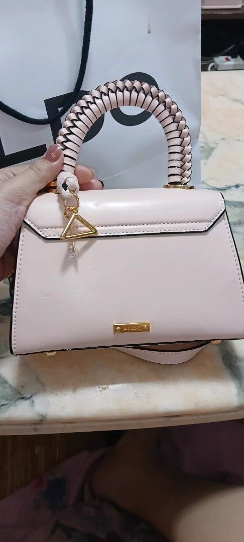 ALDO Pink Crossbody Bag with Top Handle (Category: Cross-body Bags) located in Pasig City. Submitted by elleiram05 (Listing ID 1468806498, Image 2). Description: - Authentic ALDO light pink handbag with chic black trim and gold-tone hardware - Features a trendy braided top handle and a detachable shoulder strap with side clips - Equipped with four protective metal feet on the bottom base - Spacious main compartment with a convenient internal zip 