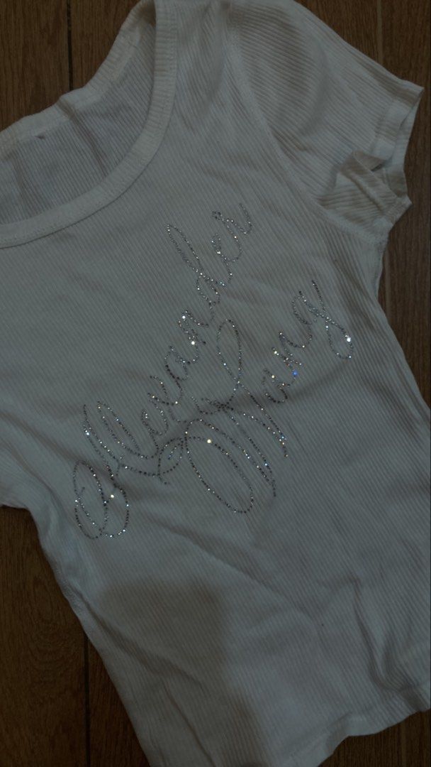 Alexander Wang Rhinestone Ribbed Crop Top White (Category: Shirts) located in Subic. Submitted by bottomjeanzgals (Listing ID 1468843072, Image 2). Description: - Color: White - Style: Cropped fit, short sleeves, round neckline - Details: Sparkly rhinestone lettering on the front - Material: Soft and stretchy cotton fabric - Versatility: Easy to style with high-waisted jeans or skirts for everyday wear.