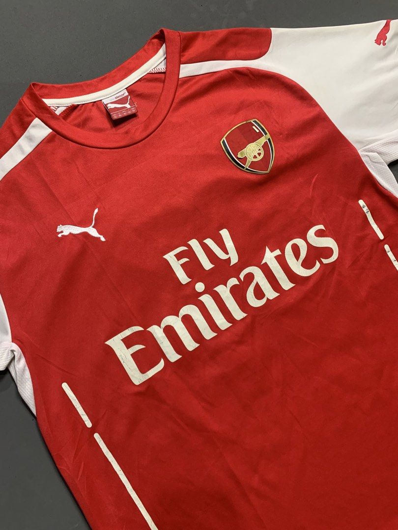 Arsenal Puma Fly Emirates Home Jersey (Category: Activewear) located in Kalibo. Submitted by gneiss2002 (Listing ID 1468752985, Image 2). Description: - Puma Arsenal home jersey - Iconic Fly Emirates chest sponsor - Classic red body with white sleeves and red Puma cats on shoulders - Stitched club crest and Puma logo - Comfortable round collar design - Must-have for Gunners fans and football kit collectors.