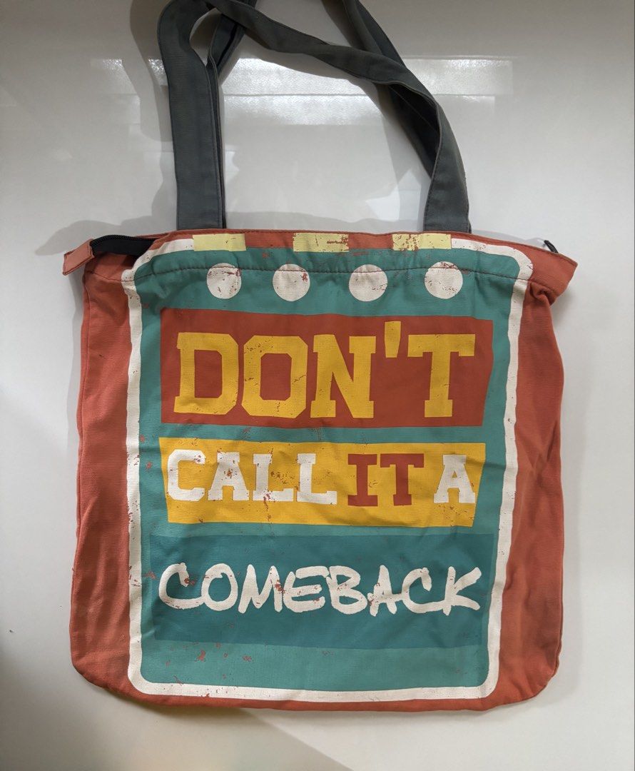 Artwork Accessories Don't Call It A Comeback Canvas Tote (Category: Tote Bags) located in Davao. Submitted by 553club (Listing ID 1468801400, Image 1). Description: - Brand/Item: Artwork Accessories orange canvas tote bag - Design: Bold 'Don't Call It A Comeback' graphic print on the front - Closure & Straps: Secure top zip closure with sturdy grey shoulder straps - Pockets: Includes one interior slip pocket and a small zippered pocket on the bac