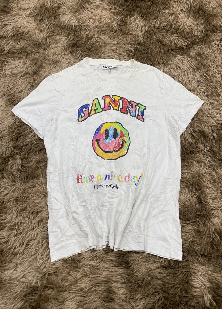 authentic GANNI Have A Nice Day Smiley T-Shirt White (Category: Shirts) located in Cagayan de Oro. Submitted by sepamorash53558 (Listing ID 1468733021, Image 2). Description: - Brand: GANNI - Color: White - Material: Soft cotton, Made in Portugal - Fit: Relaxed, casual everyday piece - Design: Colorful crayon-style 'GANNI' lettering with smiley face and 'Have a nice day! Please recycle' text - Flaw: Minor yellowing on the collar due to wear and a