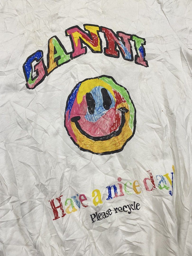authentic GANNI Have A Nice Day Smiley T-Shirt White (Category: Shirts) located in Cagayan de Oro. Submitted by sepamorash53558 (Listing ID 1468733021, Image 3). Description: - Brand: GANNI - Color: White - Material: Soft cotton, Made in Portugal - Fit: Relaxed, casual everyday piece - Design: Colorful crayon-style 'GANNI' lettering with smiley face and 'Have a nice day! Please recycle' text - Flaw: Minor yellowing on the collar due to wear and a