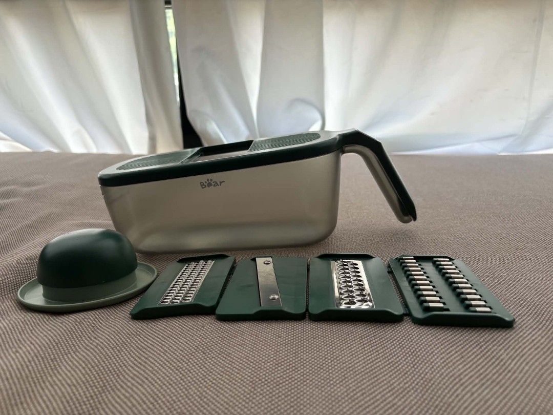 Bear Multi-Function Vegetable Slicer and Grater with 4 Blades (Category: Knives & Chopping Boards) located in Marikina City. Submitted by wildmoon7459 (Listing ID 1468925280, Image 3). Description: - Brand: Bear Multi-Function Vegetable Slicer & Grater Set - Color: Dark green and translucent grey - Blades: 4 interchangeable stainless steel blades for slicing, shredding, and grating - Safety: Includes a hand guard tool to protect fingers - Storage