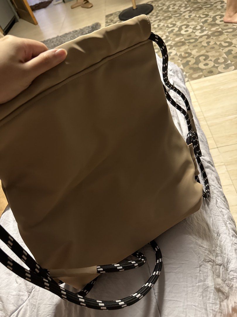 Beige drawstring backpack with black and white rope straps (Category: Backpacks) located in Caloocan City. Submitted by tootsief (Listing ID 1468877808, Image 2). Description: - Color & Material: Beige nylon with brown fabric lining - Straps: Thick, durable black and white patterned rope straps - Storage: Main zippered compartment and front exterior zip pocket for quick access - Design: Lightweight and easy to pack - Best For: School, gym session