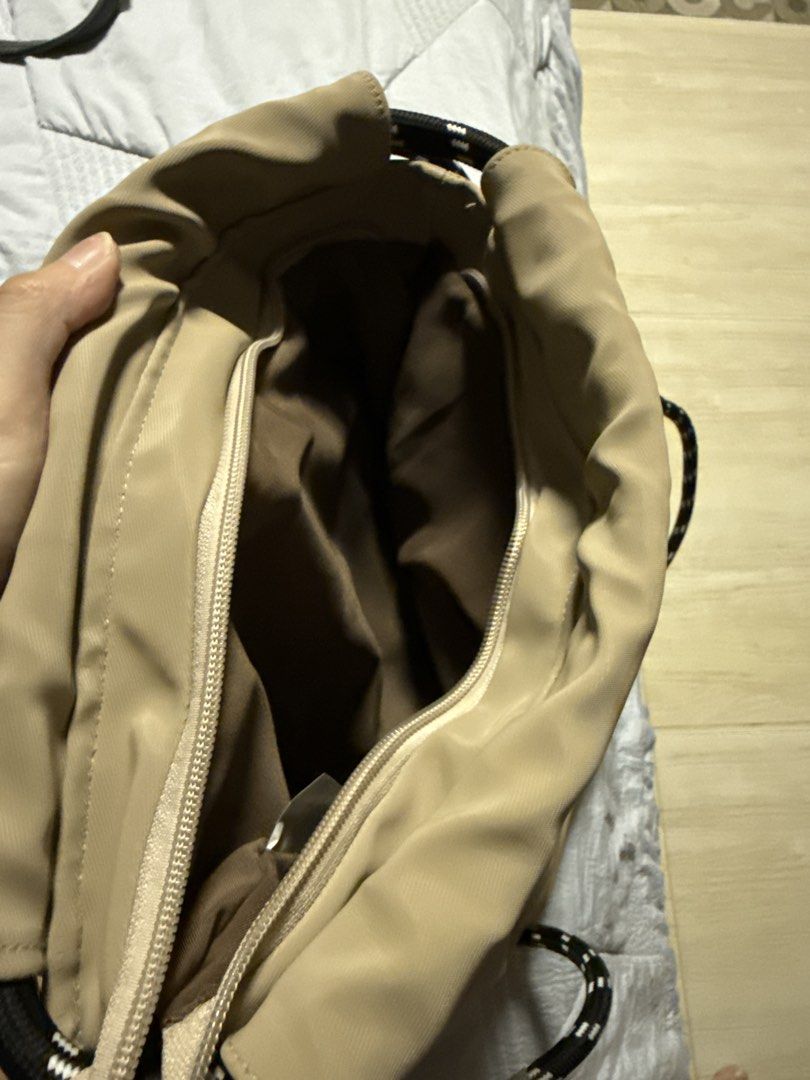 Beige drawstring backpack with black and white rope straps (Category: Backpacks) located in Caloocan City. Submitted by tootsief (Listing ID 1468877808, Image 3). Description: - Color & Material: Beige nylon with brown fabric lining - Straps: Thick, durable black and white patterned rope straps - Storage: Main zippered compartment and front exterior zip pocket for quick access - Design: Lightweight and easy to pack - Best For: School, gym session