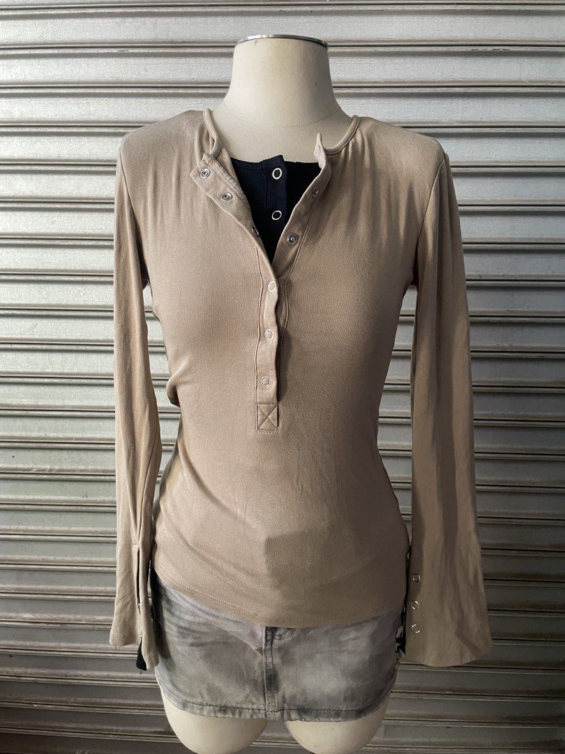 Beige Long Sleeve Henley Top with Contrast Black Layer (Category: Longsleeves) located in Davao. Submitted by riab_qt (Listing ID 1468777919, Image 2). Description: - Color: Beige with black layered inner collar and cuffs - Neckline: Henley style with silver snap buttons - Sleeves: Long flared sleeves with wrist button details - Material: Soft and stretchy ribbed fabric - Fit: Fitted cut that hugs the body - Styling tip: Looks amazing paired with