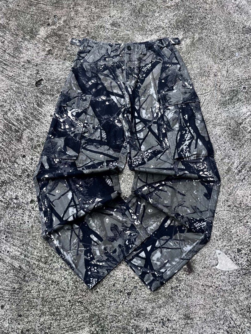 Black and Grey Tree Camo Cargo Pants (Category: Jeans) located in Manila. Submitted by fiercefox.4ae806 (Listing ID 1468881104, Image 1). Description: - Pattern: Tree bark camouflage in stylish black and grey tones - Material: Heavy-duty, durable cotton fabric - Fit: Relaxed fit through the leg for all-day comfort - Storage: Multiple utility pockets on both legs - Closure: Classic button fly - Adjustability: Adjustable waist tabs for a customized