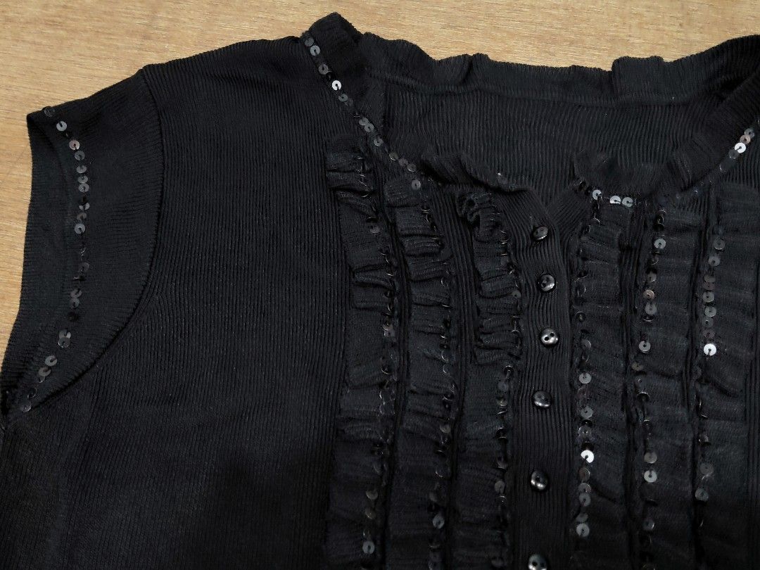 Black Knit Blouse with Sequin and Ruffle Details (Category: Blouses) located in San Juan City. Submitted by rhennx (Listing ID 1468903752, Image 2). Description: - Color: Black - Material: Stretchy ribbed knit fabric for a comfy fit - Design: Short sleeves with button-down front - Accents: Eye-catching ruffle panel and collar lined with small shiny sequins - Versatility: Great for casual outings or dressed up for the evening.