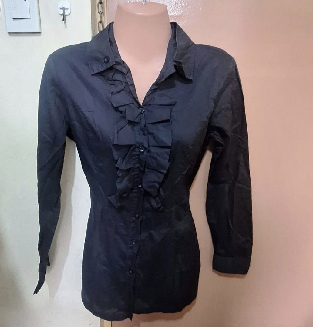 Black Long Sleeve Blouse with Ruffle Front (Category: Blouses) located in Manila. Submitted by noblegem04 (Listing ID 1468919731, Image 1). Description: - Color: Black - Style: Button-down blouse with fitted waist - Details: Ruffled front placket, classic collared neckline, matching black buttons - Sleeves: Long sleeves - Material: Smooth, comfortable fabric - Versatility: Easy to dress up for work or pair with casual pants.
