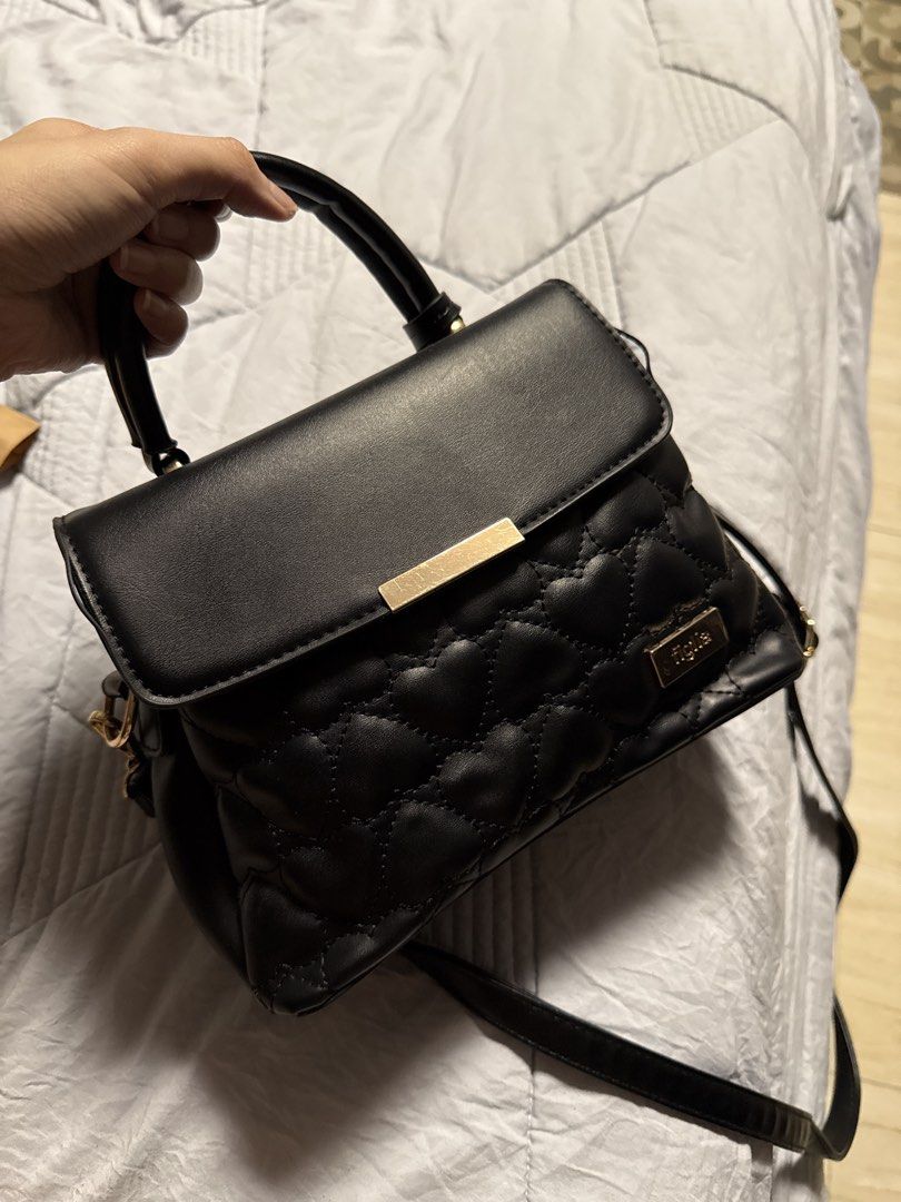 Black Quilted Heart Handbag (Category: Luxury Bags & Wallets) located in Caloocan City. Submitted by tootsief (Listing ID 1468865842, Image 1). Description: - Style: Structured black handbag with a trendy quilted heart pattern on the front flap - Hardware: Elegant gold-tone accents including a front metal bar, logo charm, and zipper pulls - Versatility: Comes with a sturdy top handle and a detachable, adjustable shoulder strap - Storage: Multiple