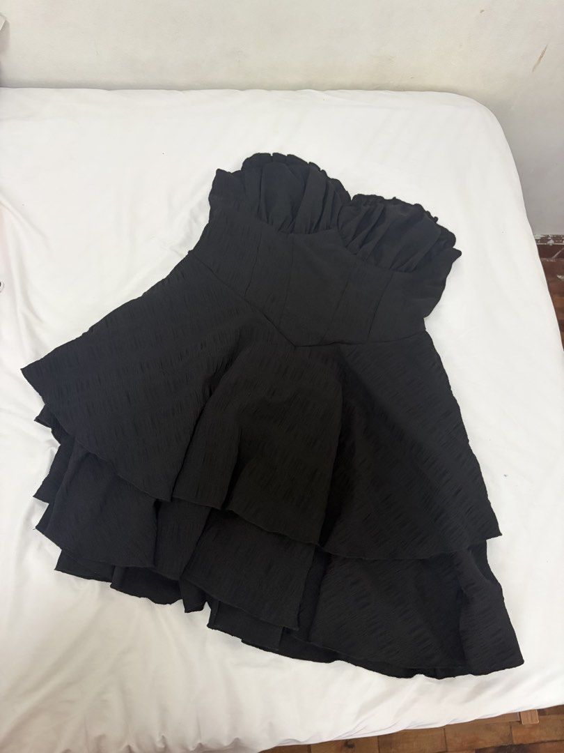 Black Strapless Ruffle Tiered Mini Dress (Category: Dresses) located in Las Pinas. Submitted by thriftedfinds_ (Listing ID 1468868959, Image 1). Description: - Style: Black strapless party dress - Neckline: Sweetheart neckline with gathered bust detail - Skirt: Multi-layered ruffled skirt for a voluminous, flared shape - Fabric: Textured material throughout - Fit: Easy pull-on style - Occasion: Ideal for parties, nights out, or dates - Versatilit