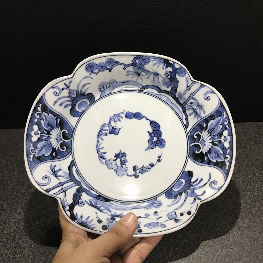 Blue and white ceramic scalloped decorative plate (Category: Dinnerware & Cutlery) located in Baao. Submitted by all.things.japan (Listing ID 1468746564, Image 2). Description: 9.0 x 8.25 x 1.75 inches - Scalloped ceramic plate with classic blue and white floral and pine tree design - Features a detailed circular center arrangement and scrollwork on the base - Stamped with a blue maker mark inside the foot ring - Premium glossy glaze finish with 