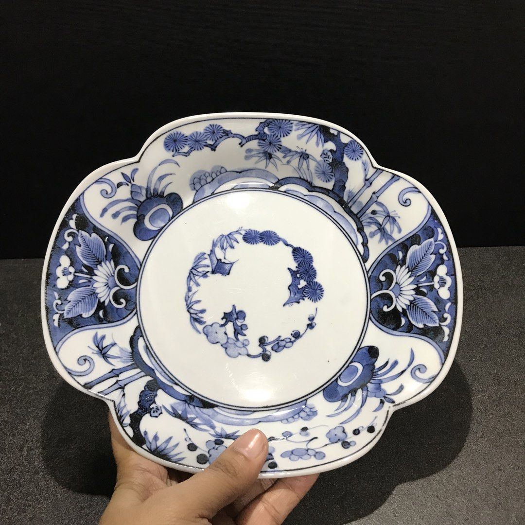 Blue and white ceramic scalloped decorative plate (Category: Dinnerware & Cutlery) located in Baao. Submitted by all.things.japan (Listing ID 1468746564, Image 3). Description: 9.0 x 8.25 x 1.75 inches - Scalloped ceramic plate with classic blue and white floral and pine tree design - Features a detailed circular center arrangement and scrollwork on the base - Stamped with a blue maker mark inside the foot ring - Premium glossy glaze finish with 