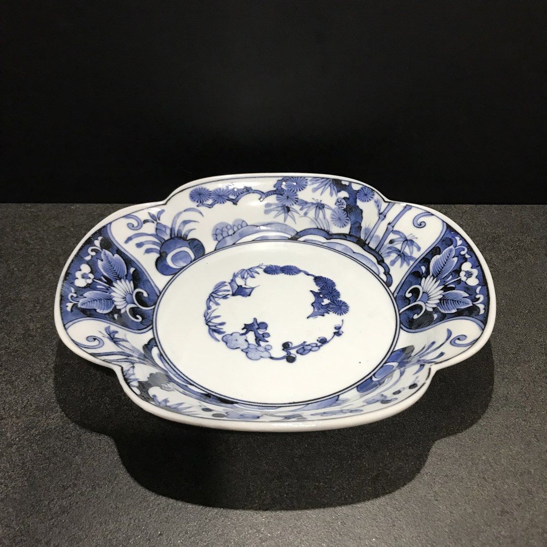 Blue and white ceramic scalloped decorative plate (Category: Dinnerware & Cutlery) located in Baao. Submitted by all.things.japan (Listing ID 1468746564, Image 1). Description: 9.0 x 8.25 x 1.75 inches - Scalloped ceramic plate with classic blue and white floral and pine tree design - Features a detailed circular center arrangement and scrollwork on the base - Stamped with a blue maker mark inside the foot ring - Premium glossy glaze finish with 