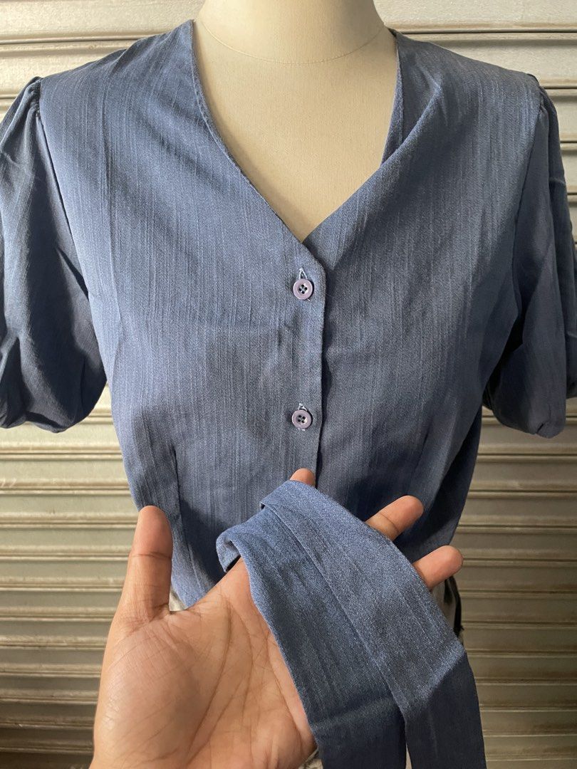 Blue Button-Up Tie Front Short Sleeve Crop Top (Category: Blouses) located in Davao. Submitted by riab_qt (Listing ID 1468776005, Image 3). Description: - Color: Blue - Style: Short sleeve crop top with V-neckline and button-down front - Details: Puffy shoulders and trendy self-tie hem - Fabric: Lightweight and textured, very comfortable - Perfect Match: Looks great with high-waisted shorts or skirts - Condition: Brand new / Excellent.