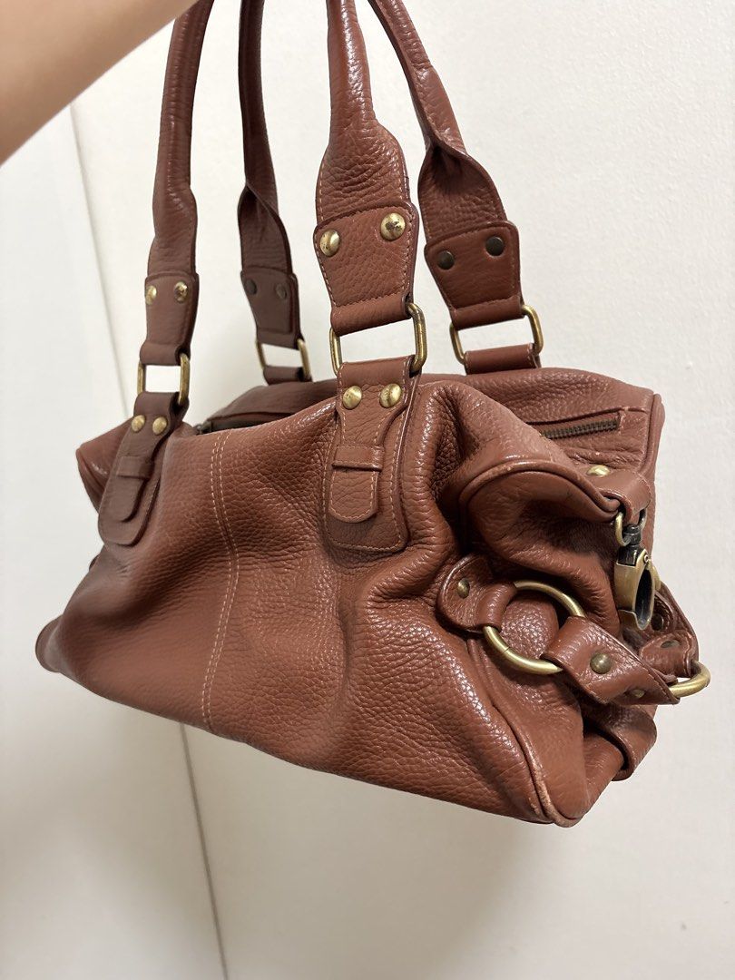 Brown Leather Shoulder Bag (Category: Shoulder Bags) located in Cabuyao City. Submitted by mhd.i (Listing ID 1468877075, Image 3). Description: Condition: Good preloved condition with signs of use. DM for more photos! Hardware: Features brass-tone metal accents. Please note there is noticeable tarnishing, color fading, and minor green oxidation on the rivets and buckles as shown in the photos. The zippers are fully functional. Leather: Soft, pebb